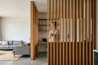 Claustra en bois en chêne séparant le salon du bureau dans un appartement contemporain au sol en béton ciré