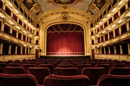Vue depuis les fauteuils d'orchestre du Théâtre Mogador vers la scène avec balcons dorés et rideaux de velours rouge